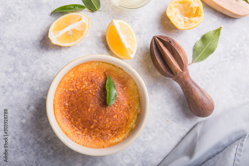 Homemade casserole, pudding, cheesecake, tart, pie or mousse with Fresh lemons and leaves on grey stone background. fruits and slice flat lay. Citrus background, copy space