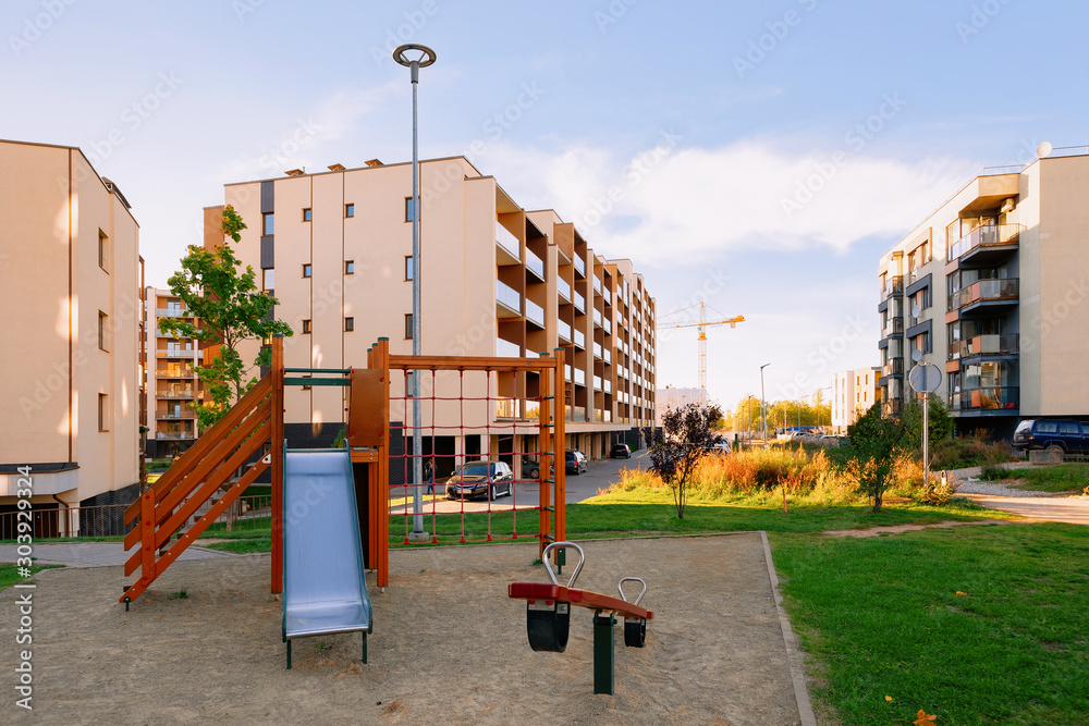 Apartment residential house facade architecture and child playground and outdoor facilities. Blue sky on the background. Apartment residential house facade architecture and child playground and outdoor facilities. Blue sky on the background.
