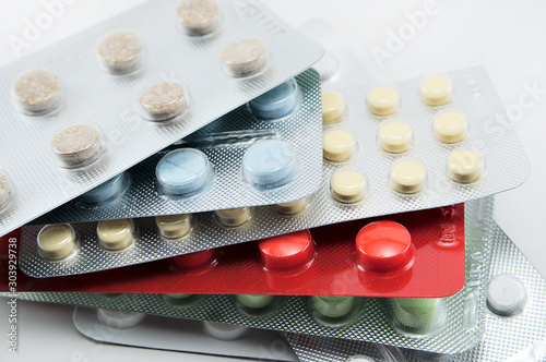 blisters with round multi-colored tablets red yellow blue white on a light background close-up, antibiotics, vitamins, analgesic antipyretic, antihistamines, antiallergic photo