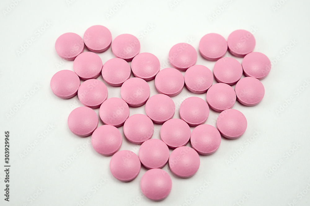 heart lined with pills on a light background