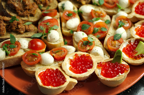 tartlets with red salmon caviar, slices of fresh salmon, cheese, avocado and tomatoes
