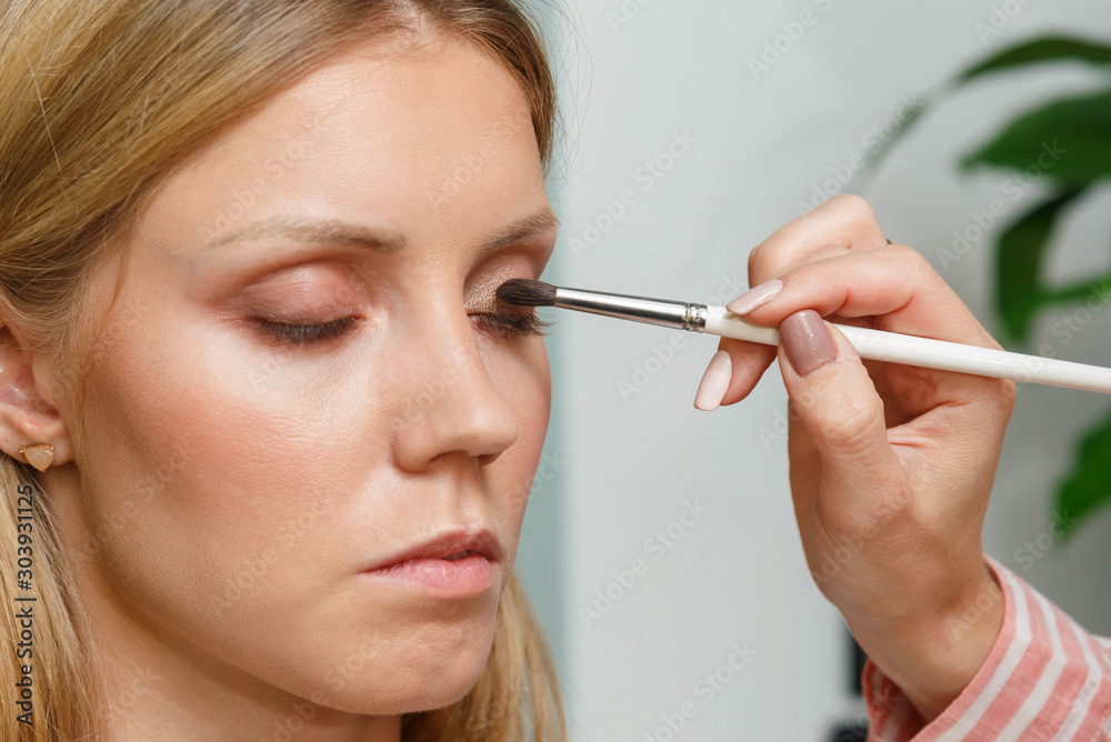 The process of creating makeup. Makeup artist working with a brush on the face of the model. The process of creating makeup. Makeup artist working with a brush on the face of the model.