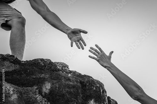 Hand reaching out for help up a mountain cliff.  photo