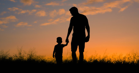 Loving father walking side by side with son holding hands. 