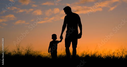 Loving father walking side by side with son holding hands.  photo