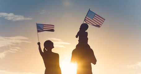 Patriotic man, woman, and child waving American flags in the air. 