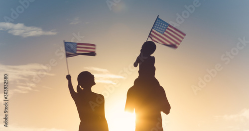 Patriotic man, woman, and child waving American flags in the air. 