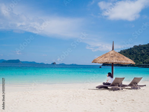 Business women sitting on seat and sun shelter on white sand beach sea view background  Travel plans in holidays or after retirement