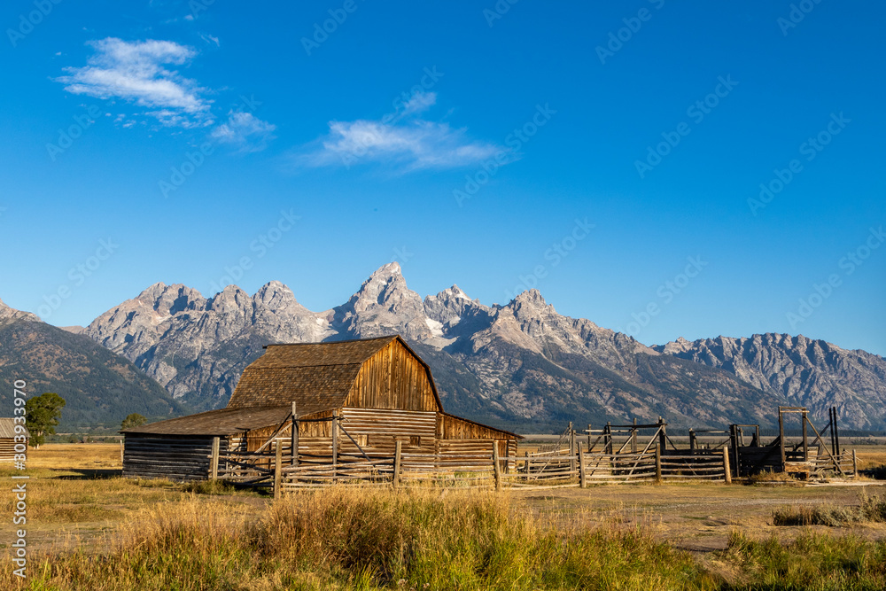 View of an old wooden barn at sunrise with mountains in the background View of an old wooden barn at sunrise with mountains in the background