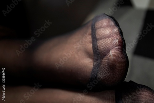 A close up portrait of a foot in black nylon pantyhose with a reinforced toe. The details of the fabric are visible. photo