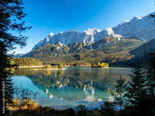 Panorama Image of Eibsee during autumn with the Zudspitze in the background and water reflections