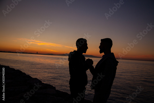 The couple jumping on the seaside on the sunset background © Korhan