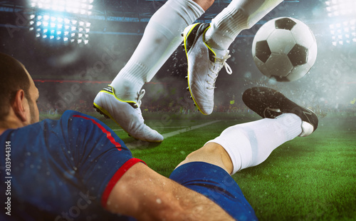 Football scene at night match with close up of two soccer players during a game match at the stadium