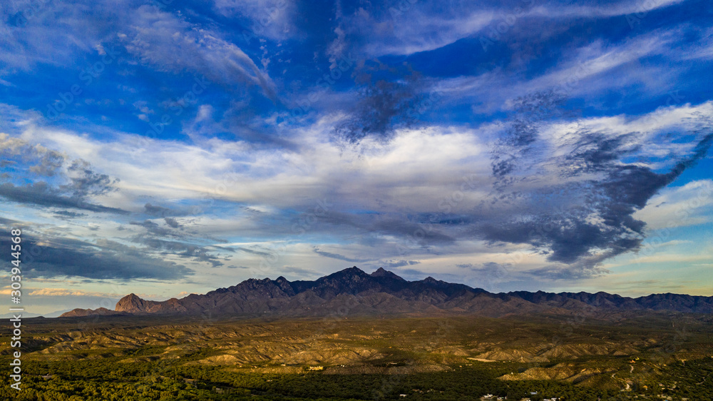 Sunset, aerial landscapes of Santa Rita Mountains from above Tubac, Arizona with warm , golden plains, purple mountains, blue sky with colorful clouds on a Fall day 