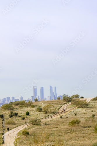 General shot of cyclist on dirt road with the Madrid skyline in the background. 