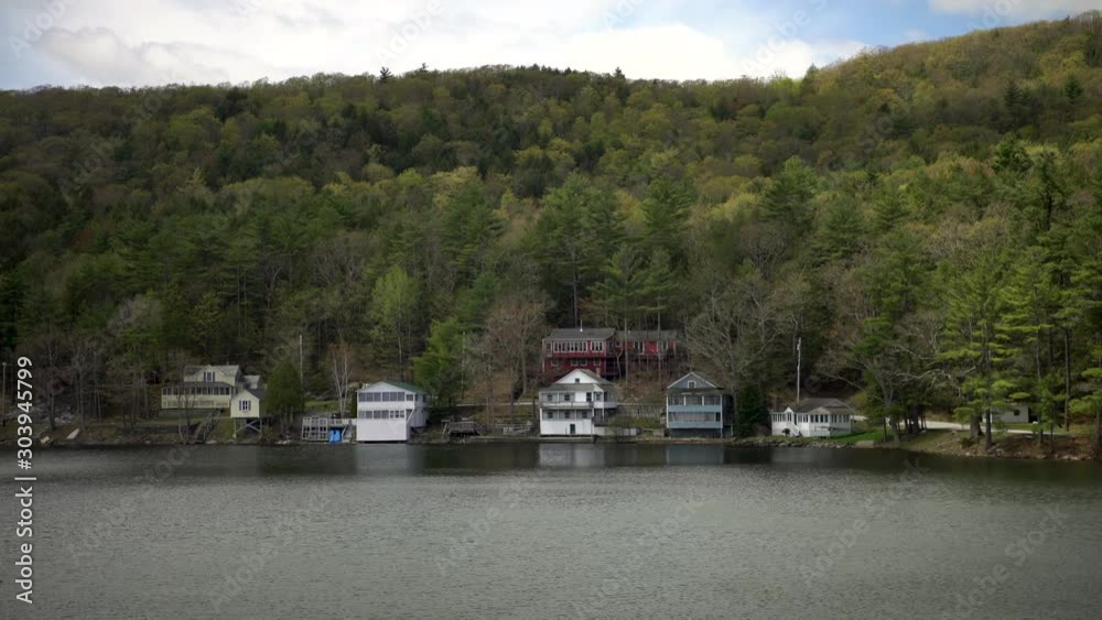 Timelapse cloud shadows passing over lake front homes surround by forest covered hills. Timelapse cloud shadows passing over lake front homes surround by forest covered hills.