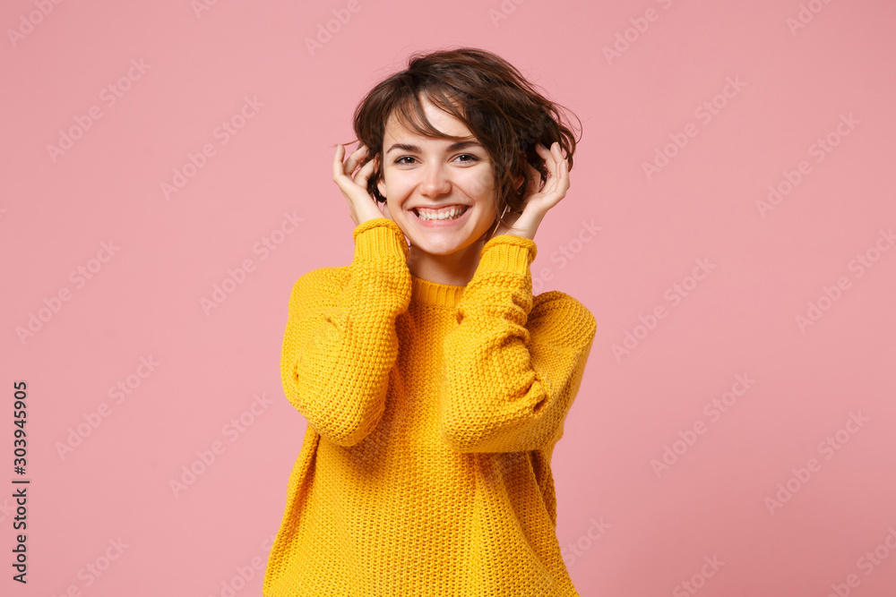 Smiling happy young brunette woman girl in yellow sweater posing isolated on pastel pink background in studio. People sincere emotions lifestyle concept. Mock up copy space. Putting hands on head. Smiling happy young brunette woman girl in yellow sweater posing isolated on pastel pink background in studio. People sincere emotions lifestyle concept. Mock up copy space. Putting hands on head.
