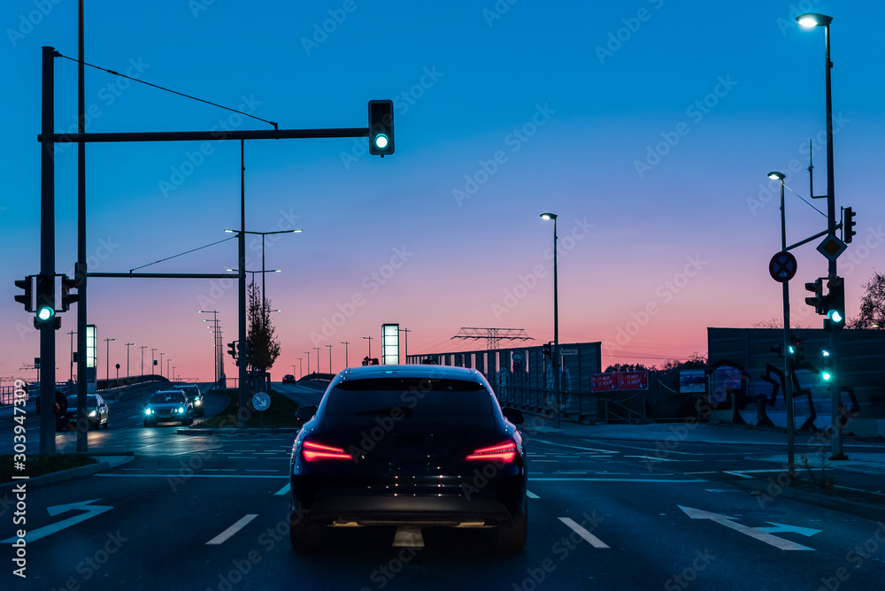 A car at a traffic light, A car at a lighted intersection, illuminated crossroads at evening, colorful