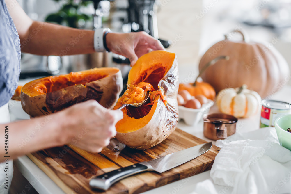 Fototapeta premium Scooping out pumpkin pie seeds from baked pumpkin