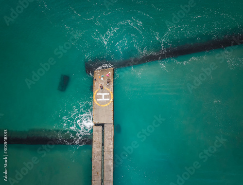Aerial view of wavebreaker with fisherman, bicycle and people on the vertiport