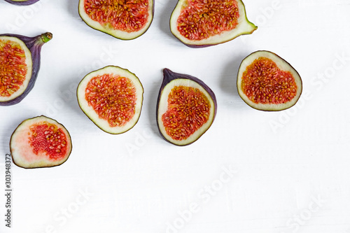 Slices of figs on a white wooden background with a place for inscription. Useful sweets for health. Blank for banner with place for inscription.