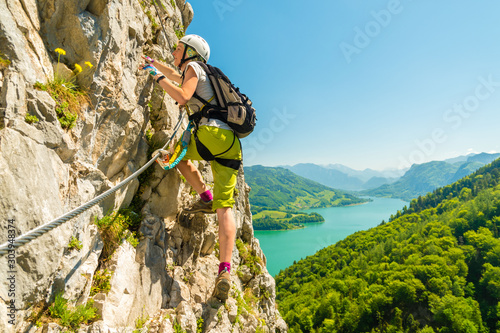 Beautiful young girl climbing Drachenwand via ferrata above scenic Mondsee lake, Alps, Austria, Europe photo