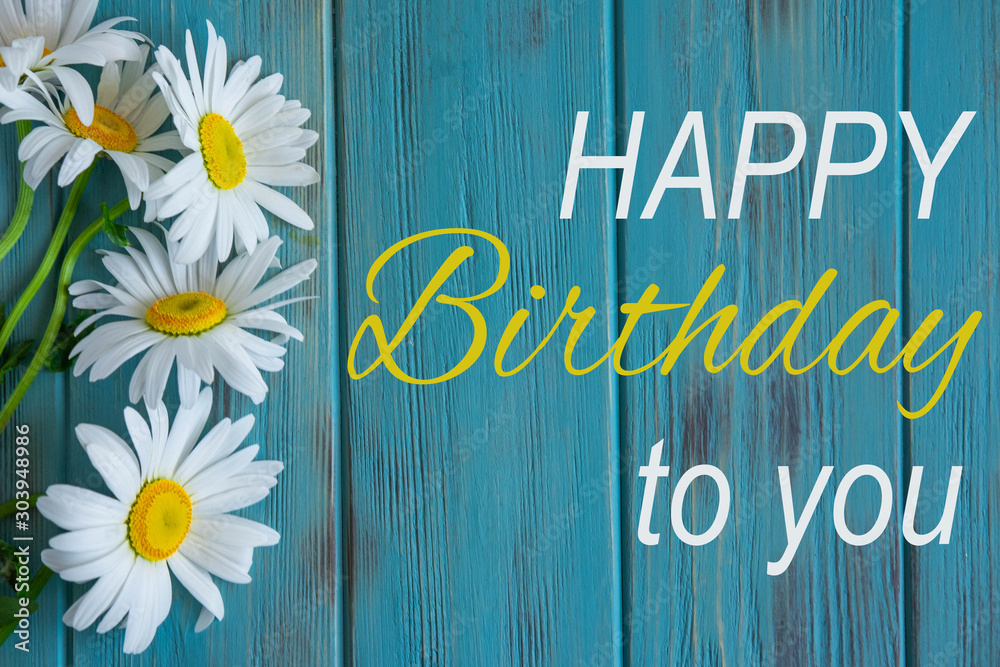 Carta da parati Happy birthday greeting card with camomile flowers on blue wooden background