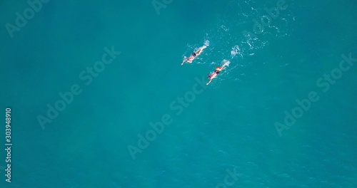 Two swimmers practicing in a long distance swim at calm ocean water. Top Down aerial footage.
