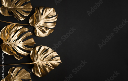 Trendy gold tropical monstera leaves on black background border frame