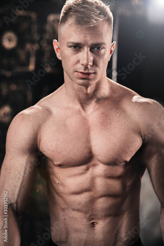 Portrait of a sexy young athletic fair-haired man with a naked torso.