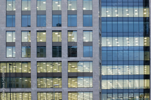 illuminated windows on the facade of a large modern office building with lights turned on on at twilight