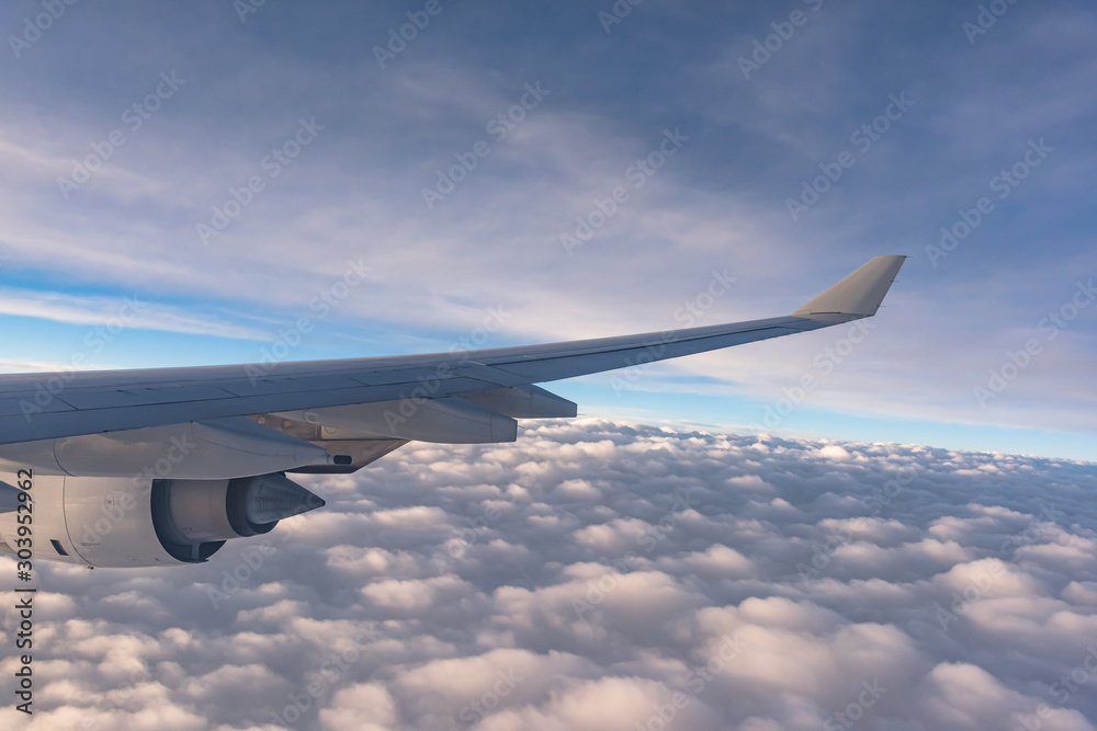 Obraz premium Wing of a plane flying high above the clouds