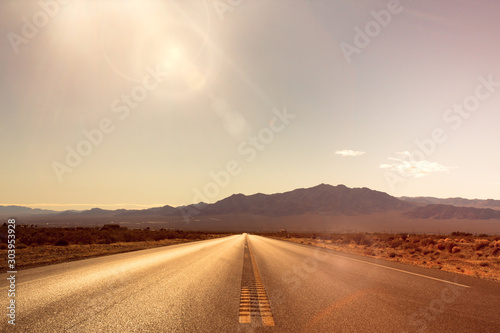 Desolate desert road with mountains with sunflare; western United Stated