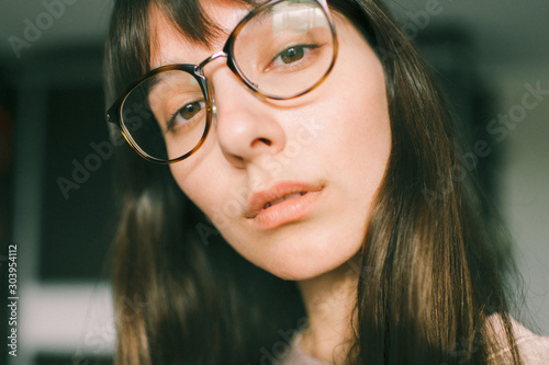 Indoor lifestyle portrait of young beautiful brunette girl posing for camera