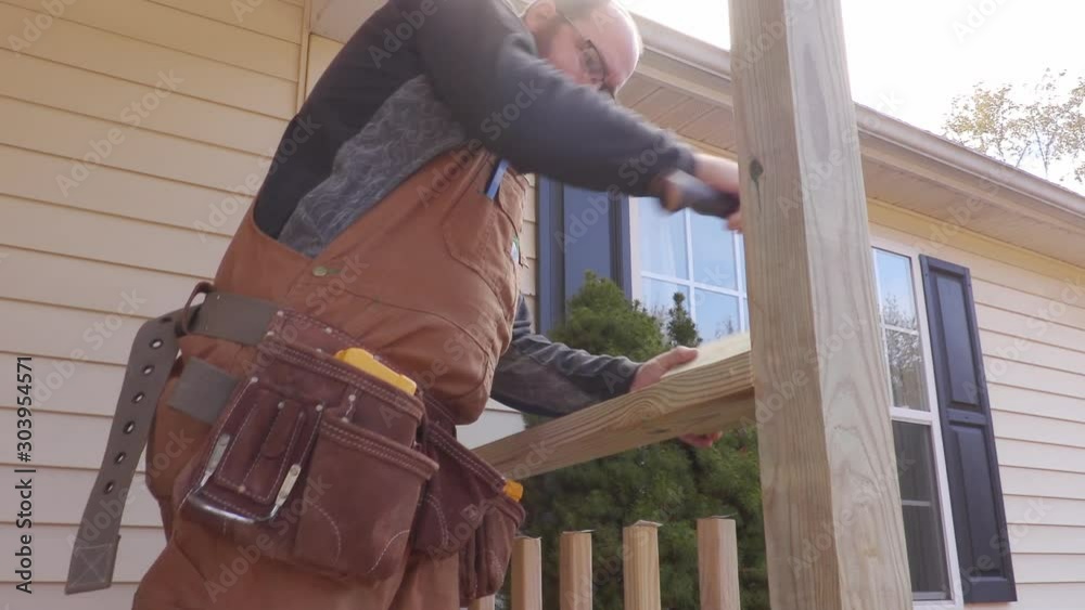 Carpenter hammering wood into place on a porch