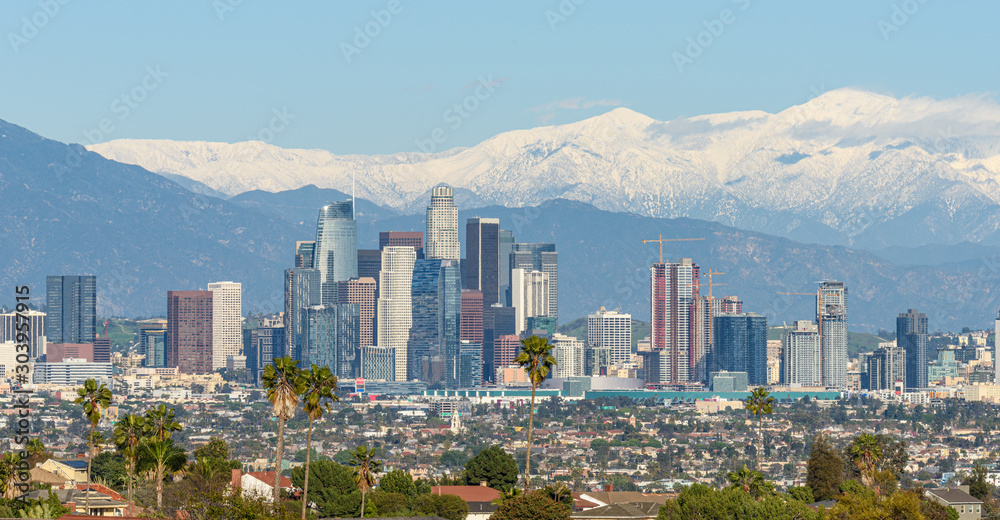 Downtown Los Angeles skyline with snow capped mountains behind at sunny day