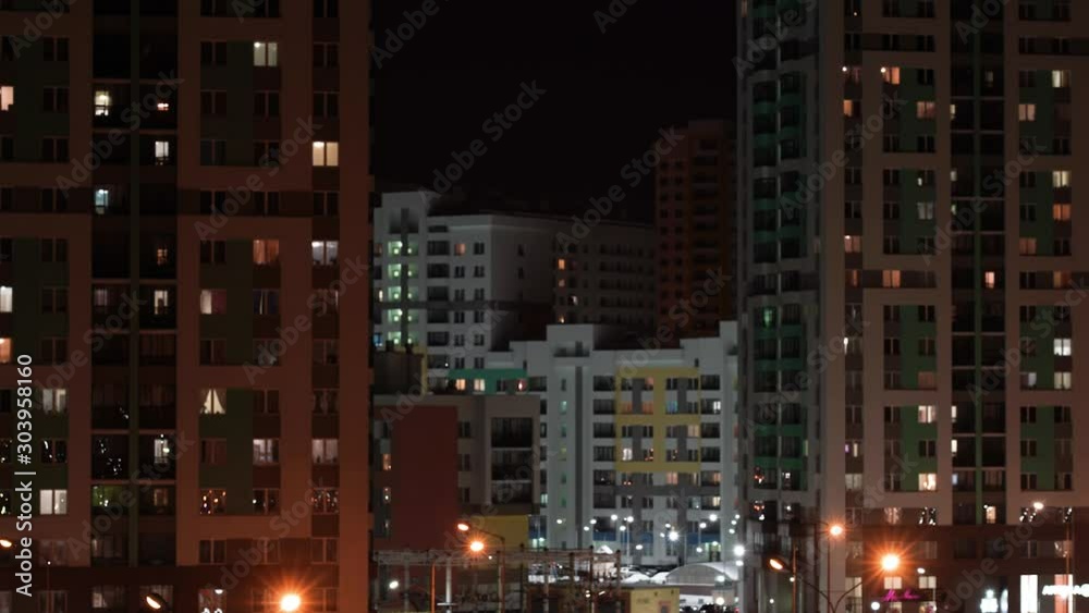Life in many apartments of multi-storey residential buildings. In the dark, the windows of apartment buildings glow. Night light in the windows of a multi-storey building.
