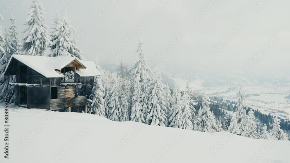 Abandoned house in snowy mountains in cold winter weather. Falling snow in winter landscape with snow covered trees. Christmas background with fir trees. Camera moves forward Abandoned house in snowy mountains in cold winter weather. Falling snow in winter landscape with snow covered trees. Christmas background with fir trees. Camera moves forward