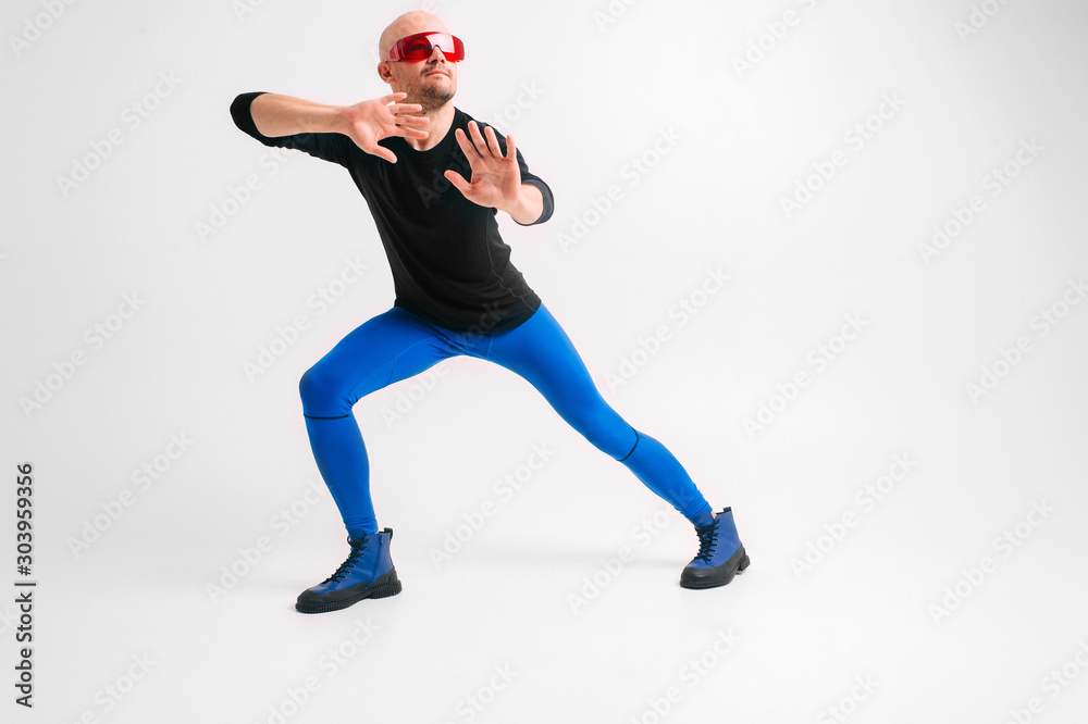 Fashion portrait of stylish man in blue tights and indigo boots stretching and exercising over white studio background. Fashion portrait of stylish man in blue tights and indigo boots stretching and exercising over white studio background.