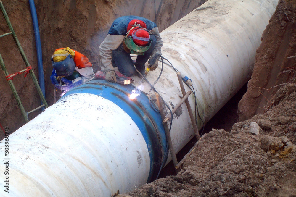 Welders are welding large steel water pipe. Stock Photo Adobe Stock
