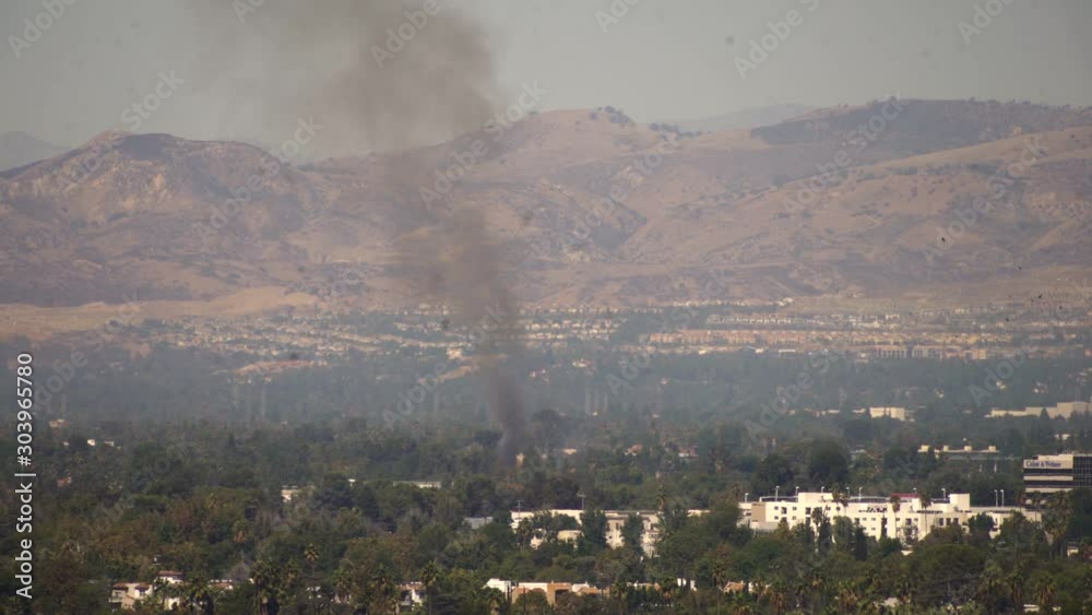 Smoke billows from the middle of a residential area in a valley town. Smoke billows from the middle of a residential area in a valley town.