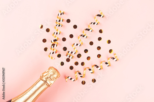 Creative New Year composition with champagne bottle and confetti on pastel pink background. © Yulia Lisitsa