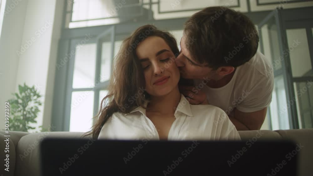 Closeup businesswoman working laptop at home. Happy couple kissing at home. Closeup businesswoman working laptop at home. Happy couple kissing at home.