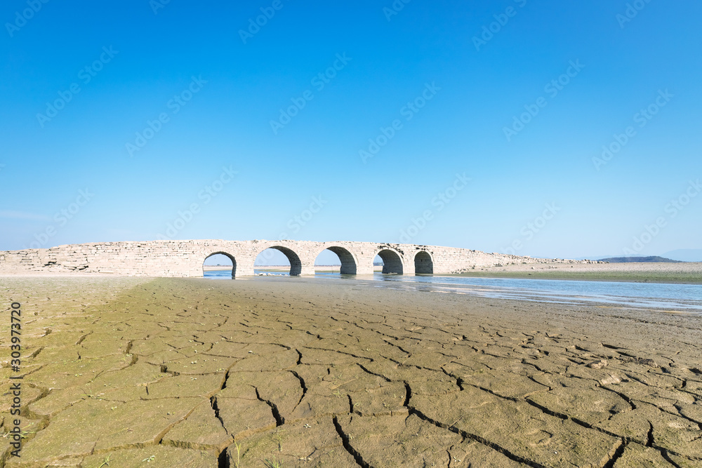 Fotografie ancient stone arch bridge against a blue sky