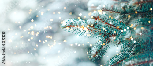 Christmas tree outdoor with snow, lights bokeh around, and snow falling, Christmas atmosphere. photo