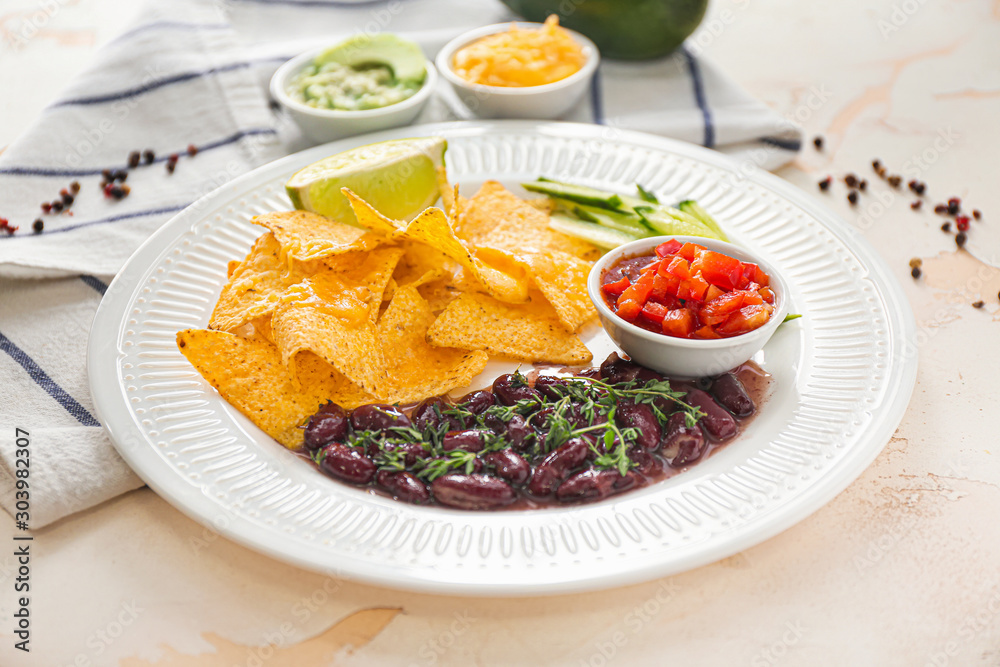 Plate with tasty nachos and beans on table