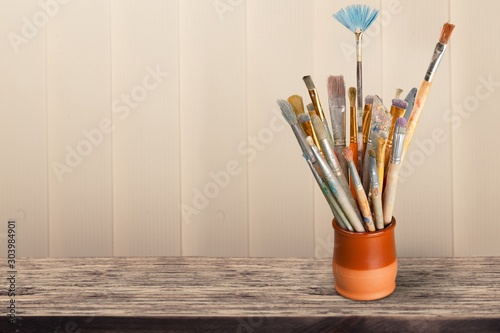 Brushes in a ceramic jar on wooden desk
