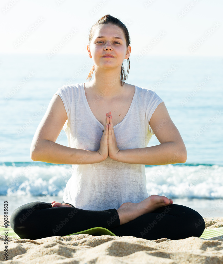 Young girl in white T-shirt is sitting and doing meditation