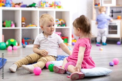 Children playing with colorful toys. Little kid girl and toddler boy in kindergarten. Children play at day care or preschool.