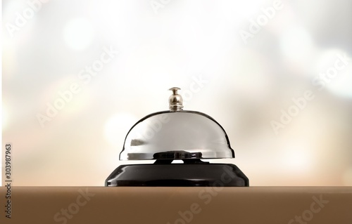 Classic metal hotel ring on wooden table with abstract bokeh background.